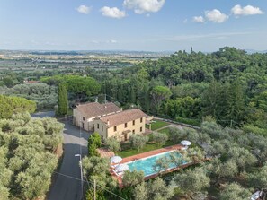 Eine Villa mit Pool, umgeben von Olivenbäumen und Blick auf die Landschaft.
