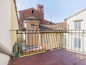 A balcony with a metal railing, a tiled floor, and a view of a building with a bell tower. - Apartment in Lucca with 2 bedrooms sleeps 4 (Lucca)