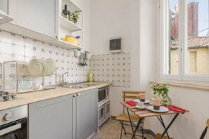 A compact kitchen with a sink, stove, and a dining area with a table and chairs. - Apartment in Lucca with 2 bedrooms sleeps 4 (Lucca)