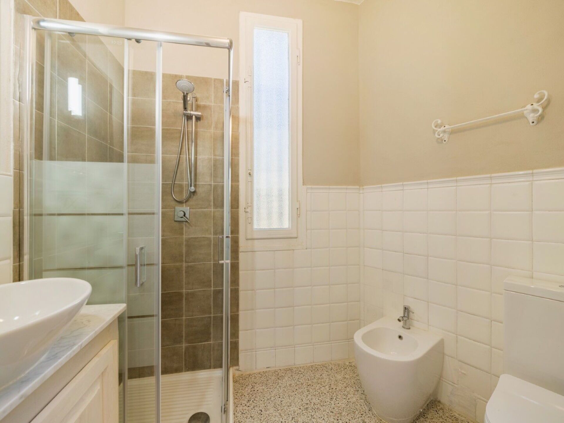 A bathroom with a glass-enclosed shower, a bidet, and a toilet.