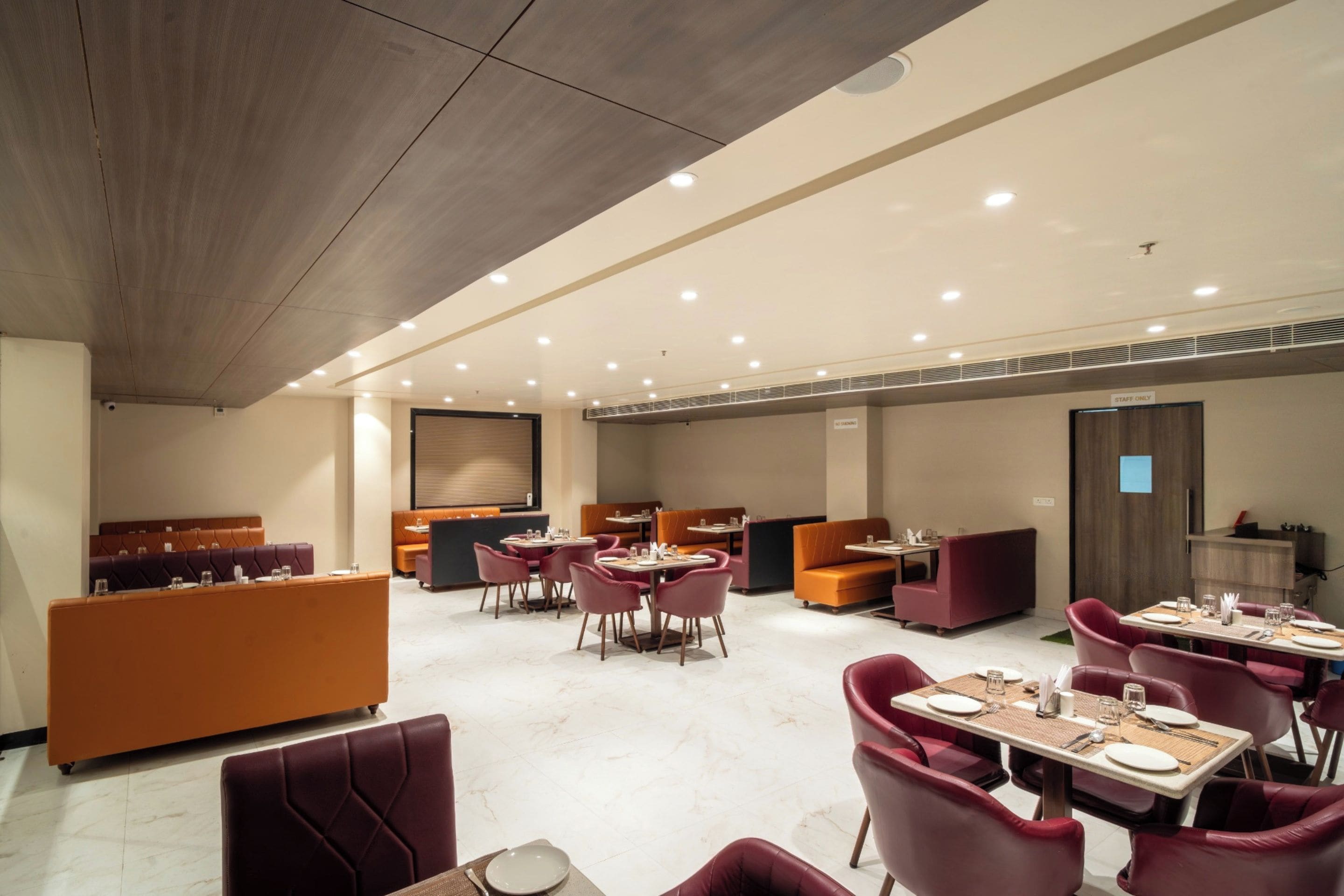 A modern restaurant with booths and tables, a wooden ceiling, and a sign indicating a staff-only area.