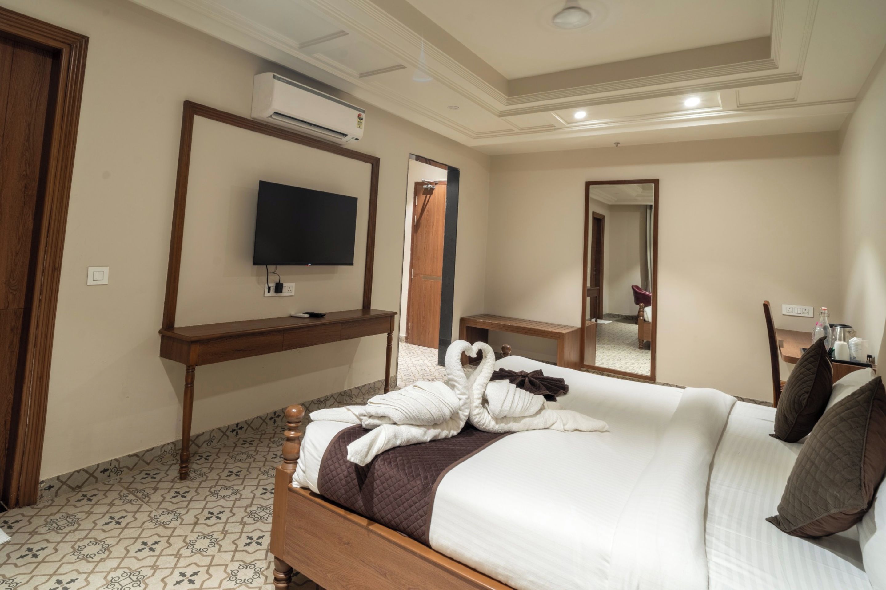 Une chambre d’hôtel avec un lit, une télévision, un bureau et un miroir.