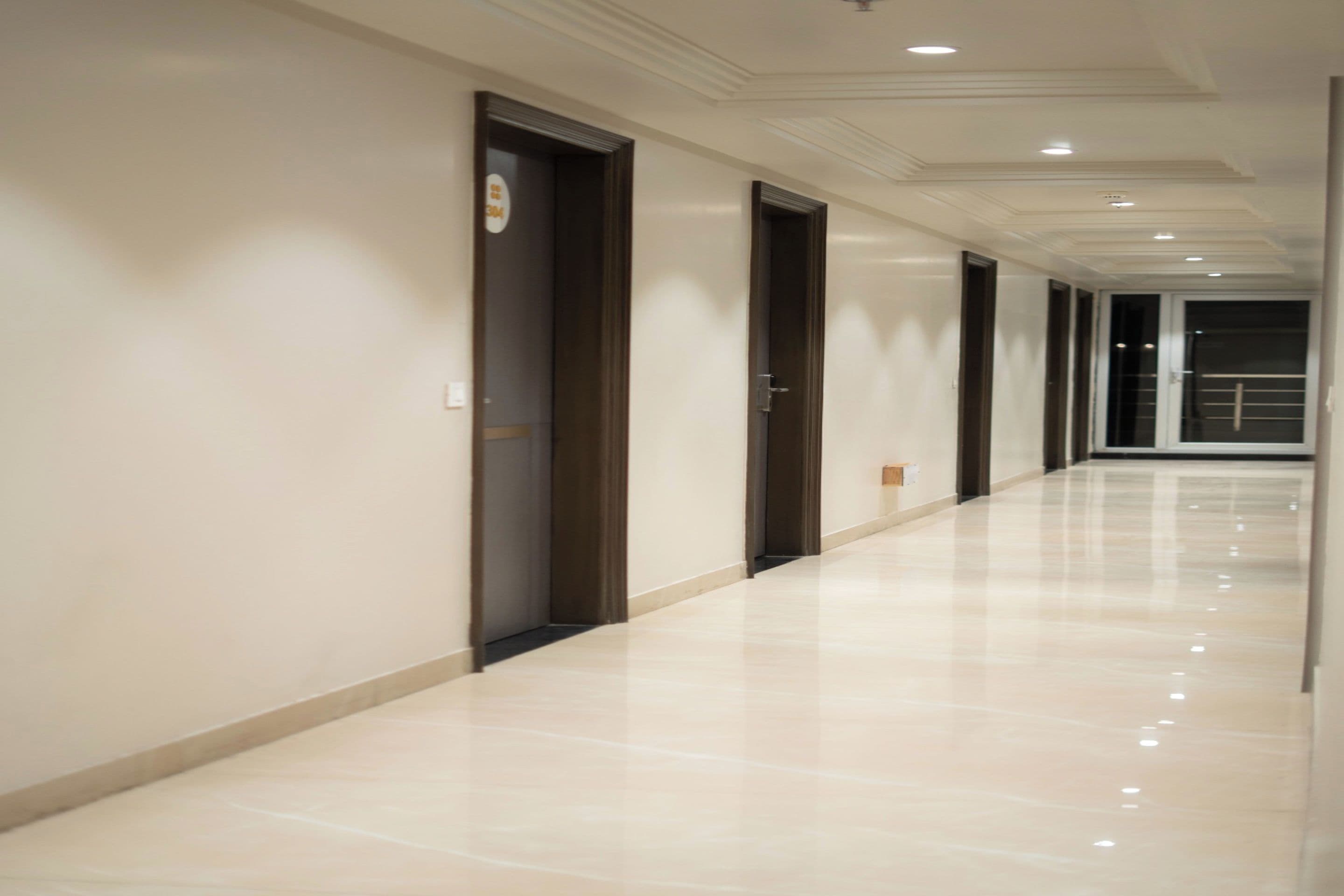 A long, narrow hallway with doors on one side and a plain wall on the other.