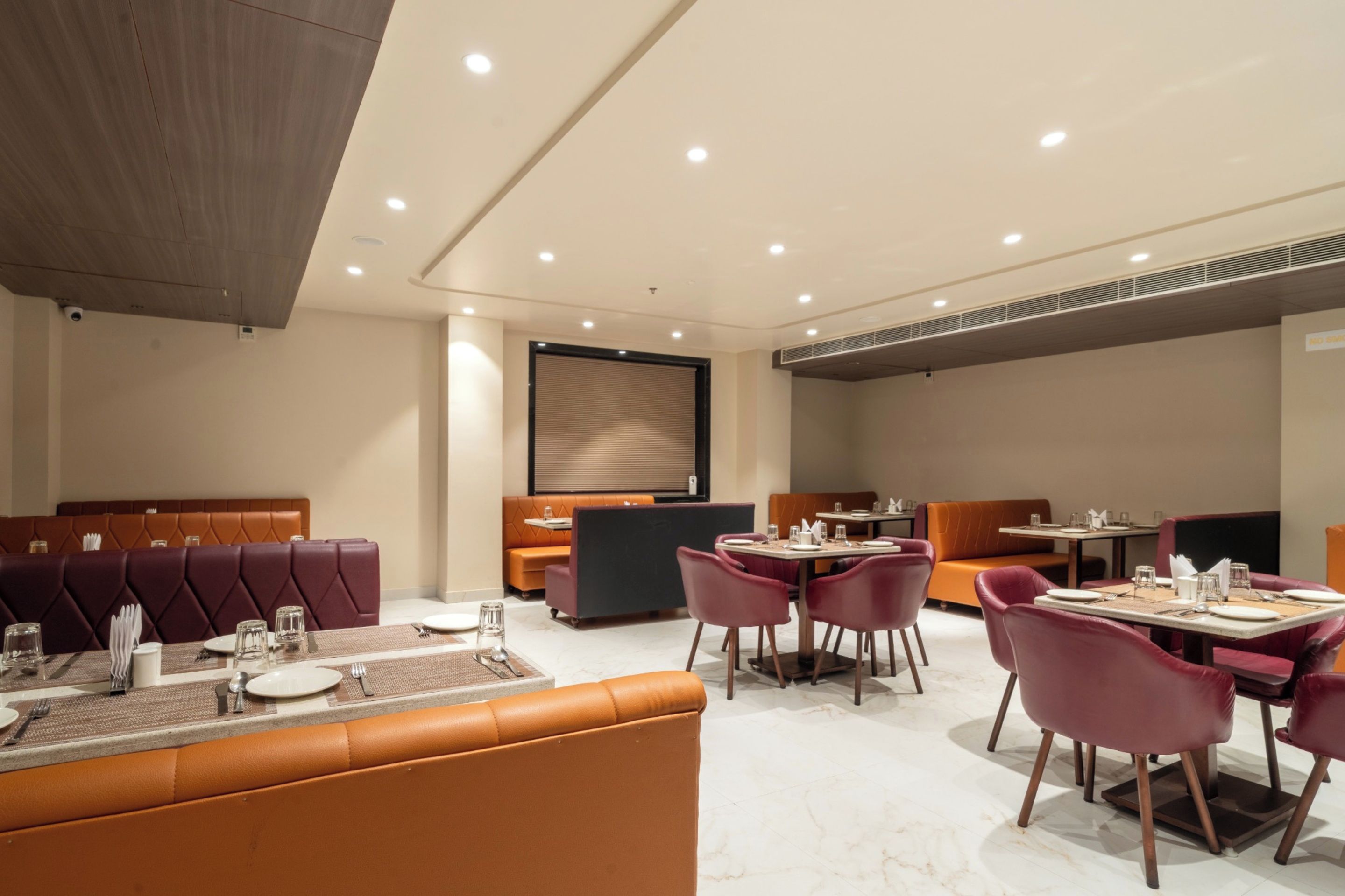 Un espace repas moderne avec des banquettes et des tables en cuir, équipé du nécessaire de base pour le service à table.