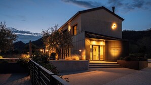 Una casa moderna de dos pisos con una entrada bien iluminada, un porche cubierto y un jardín ajardinado.