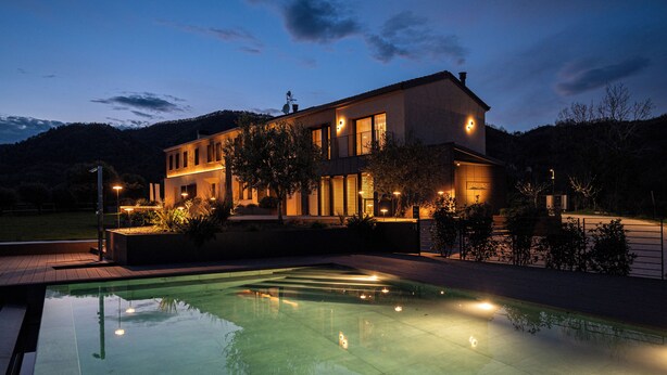 Una casa moderna con piscina al anochecer.