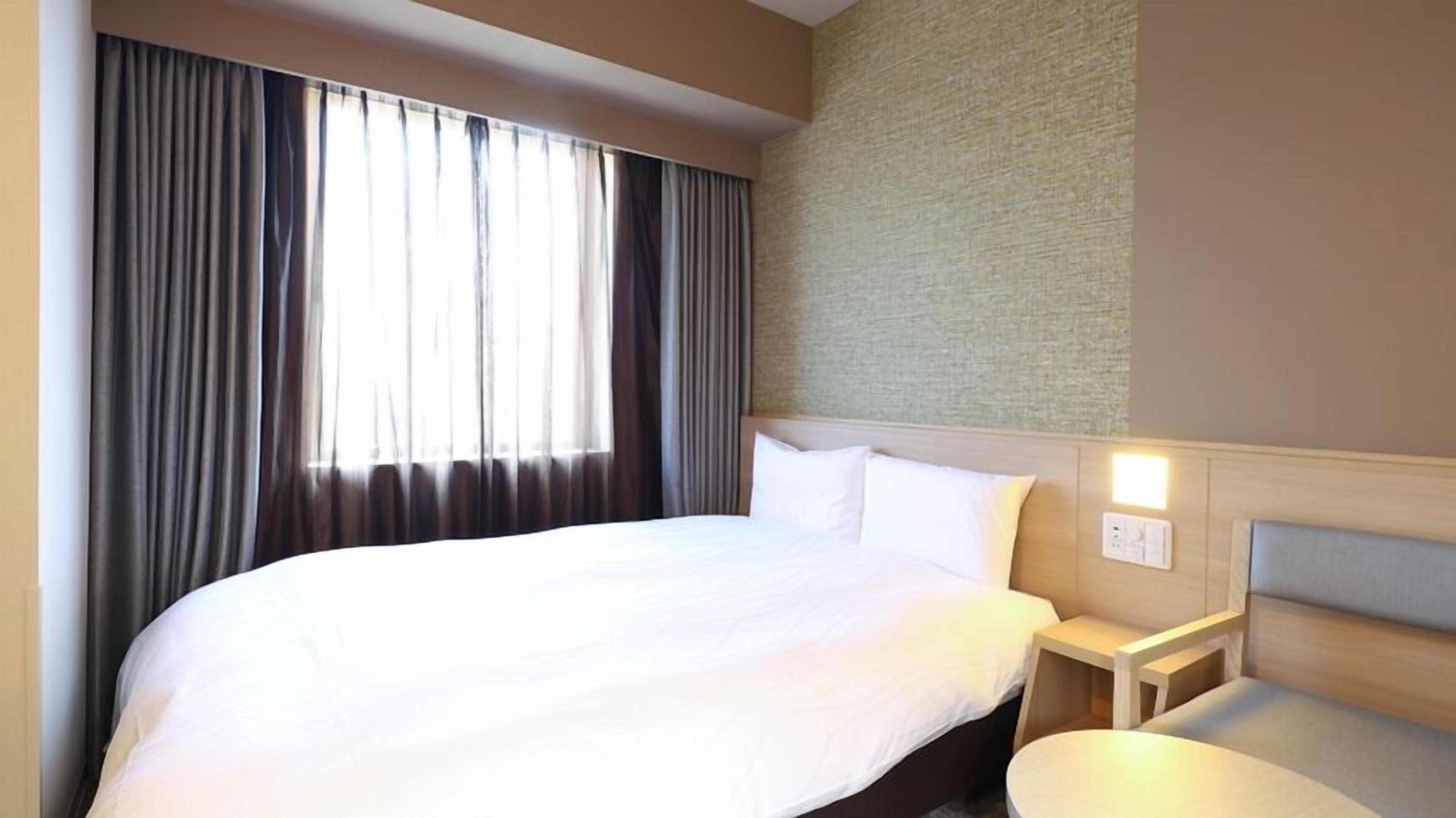 Een hotelkamer met een groot bed, een nachtkastje en een wandlamp.