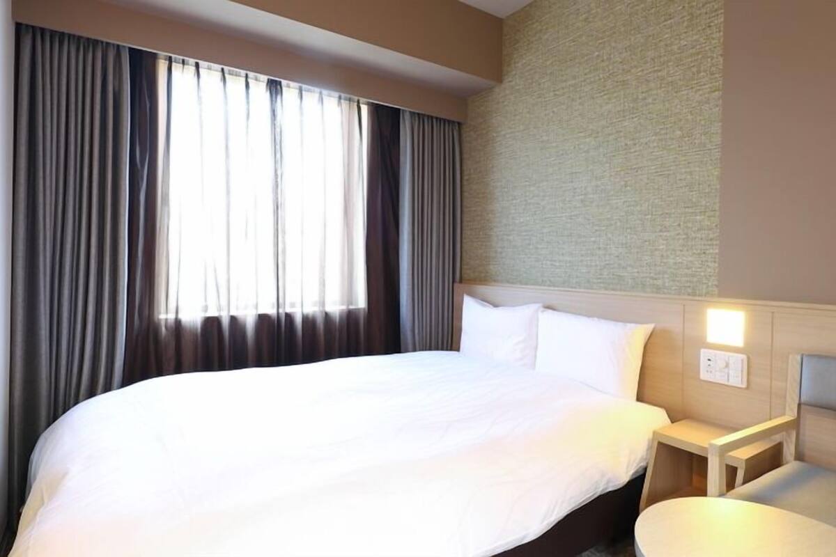 Una habitación de hotel con una cama grande, una mesita de noche y una lámpara de pared.