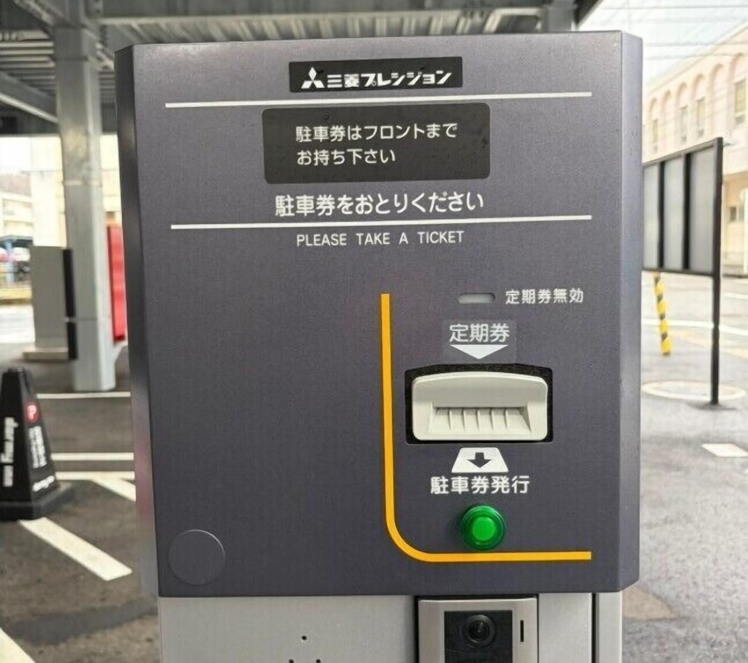 A ticket vending machine with instructions in both Japanese and English, a card slot, and a green button.