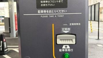 A ticket vending machine with instructions in both Japanese and English, a card slot, and a green button.
