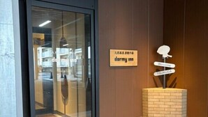 A hotel entrance with a glass door, a welcome sign, and a directional sign for Tsuruuga. - Dormy Inn Tsuruga (TSURUGA SHI)