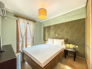 Ein Hotelzimmer mit Bett, Nachttisch, Lampe und einem Fenster mit Vorhängen.