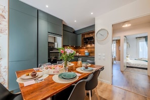 Una cucina moderna con mobili scuri, un tavolo da pranzo in legno apparecchiato con piatti, bicchieri e un vaso di fiori.