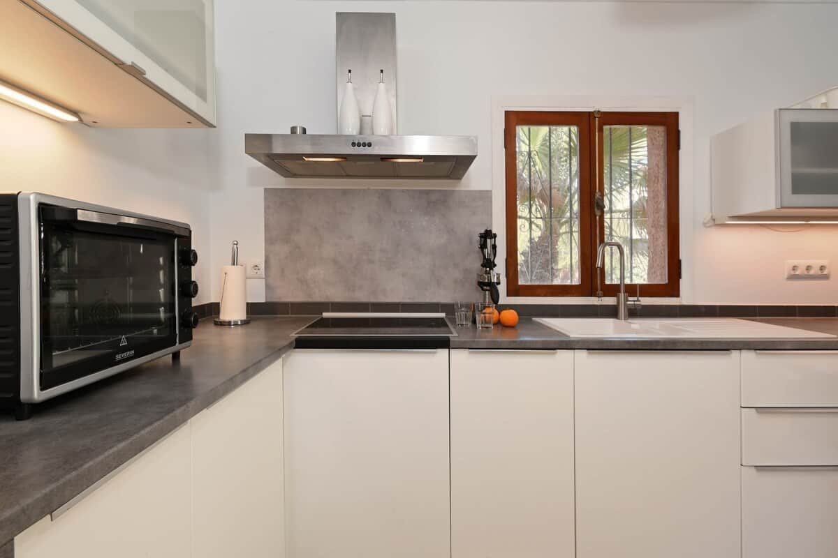 A modern kitchen with a built-in oven, a stainless steel range hood, and a double sink.