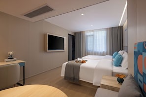 A modern hotel room with a large bed, a flat-screen TV mounted on the wall, a small table with a vase of flowers, and a seating area with a sofa and armchair. - Zhangjiajie Homeinn Boutique Hotel (Zhangjiajie)
