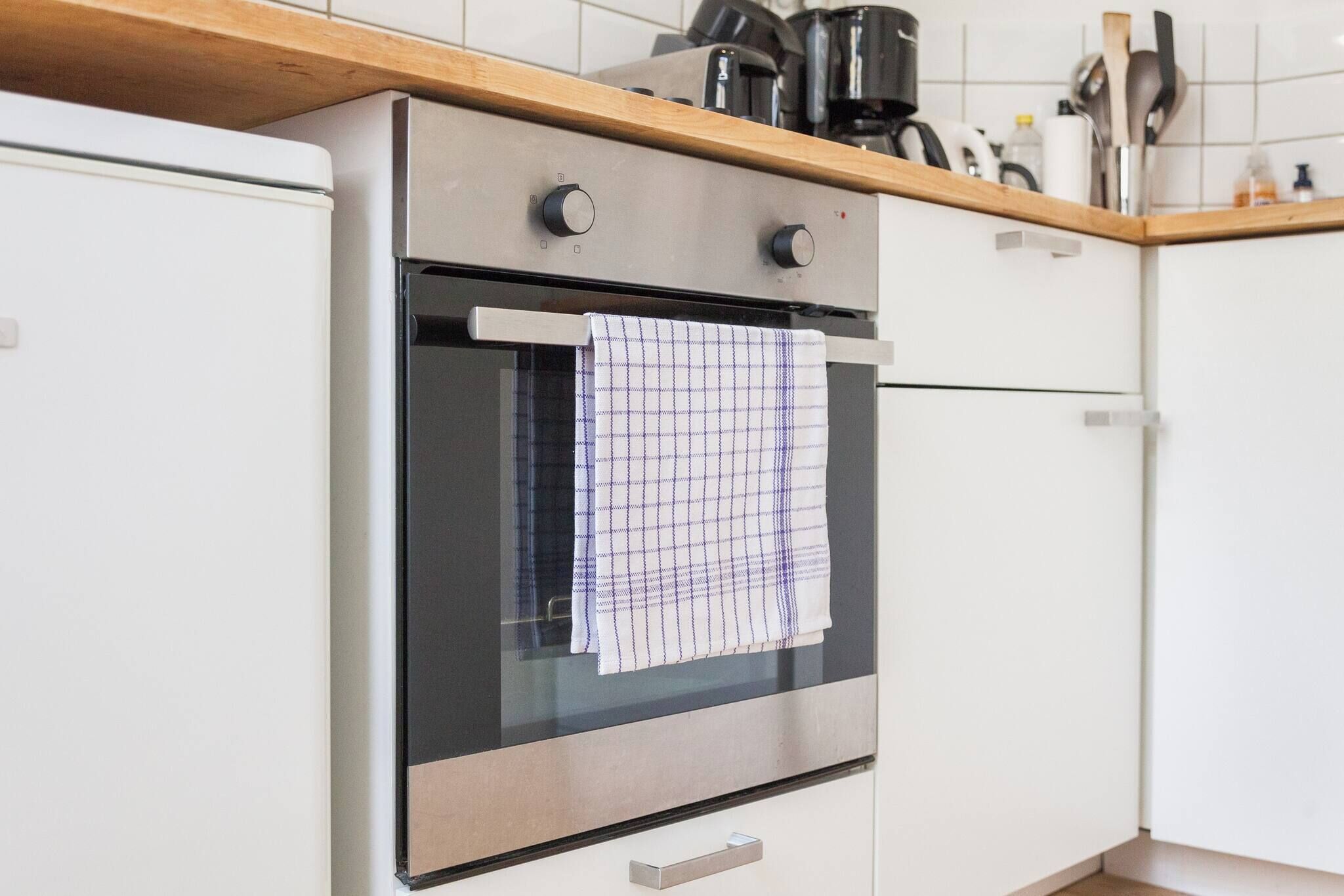 A kitchen with a stainless steel oven, a wooden countertop, and a white refrigerator.