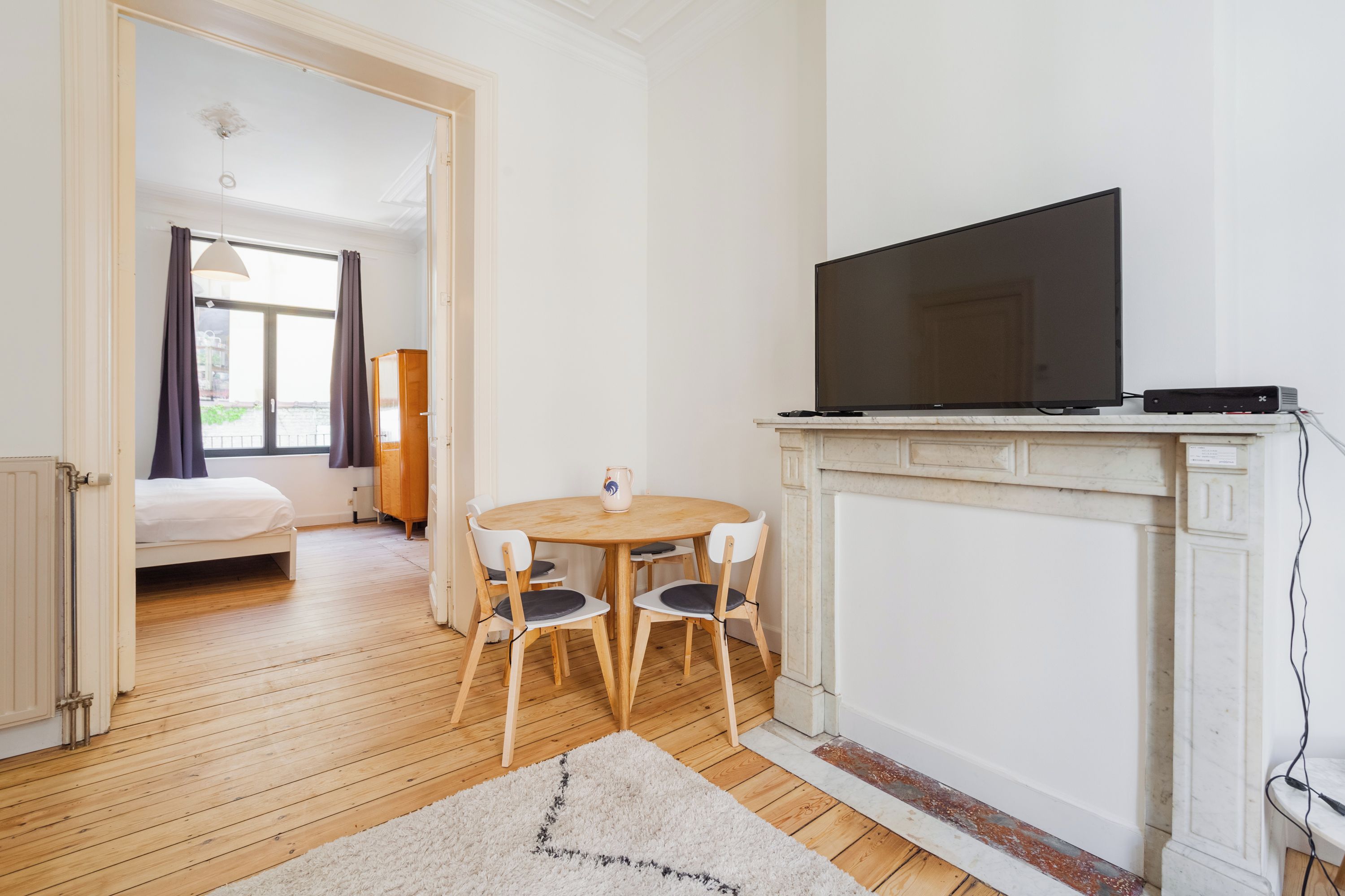 Une pièce comprenant un lit, un téléviseur, une cheminée et une table à manger avec des chaises.