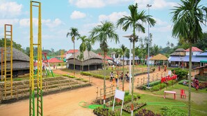 A rural village with thatched-roof houses, a playground, and a dirt path. - Hotel Banalata (Bishnupur)