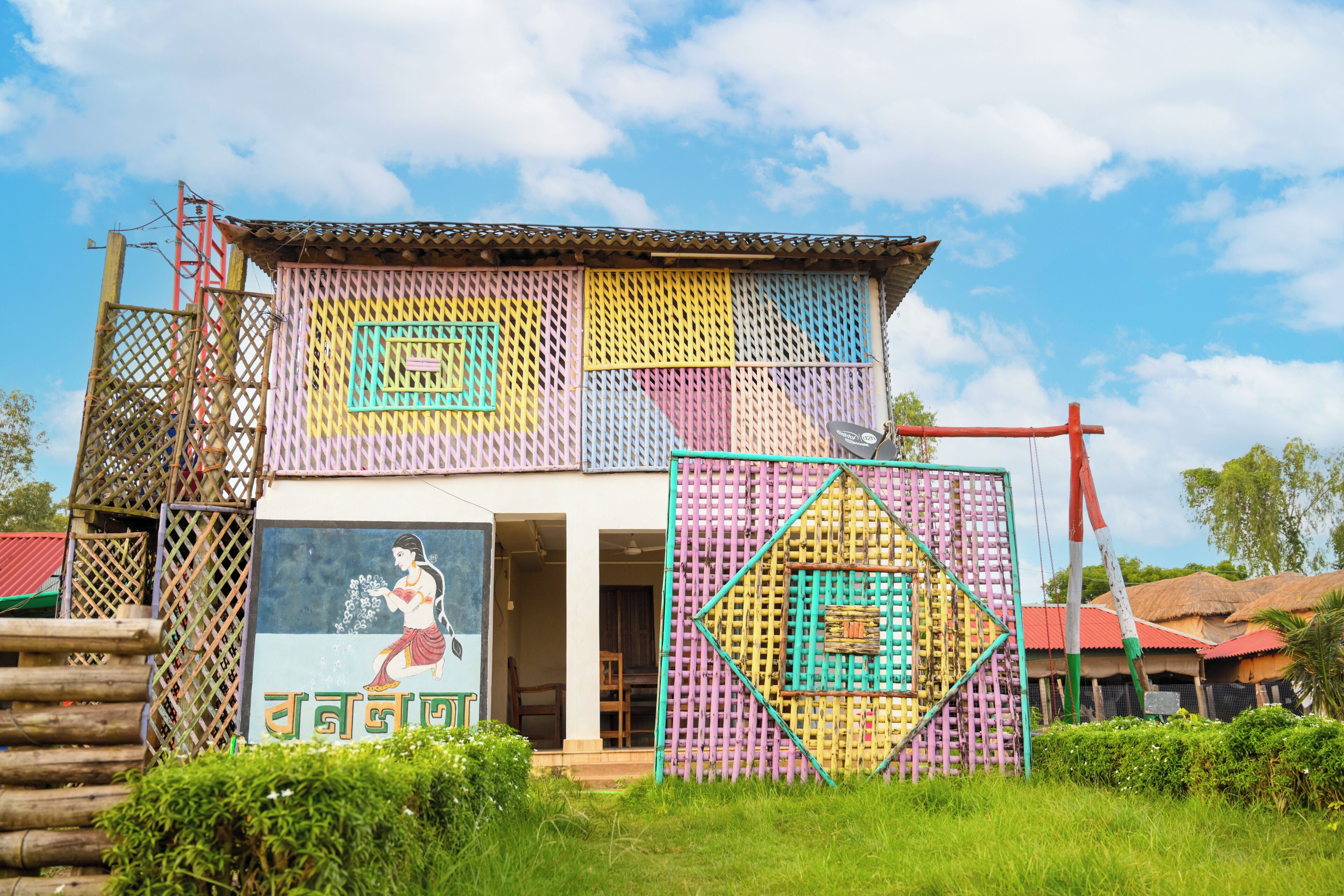A colorful building with a mural of a woman and a child, surrounded by a fence with geometric patterns.