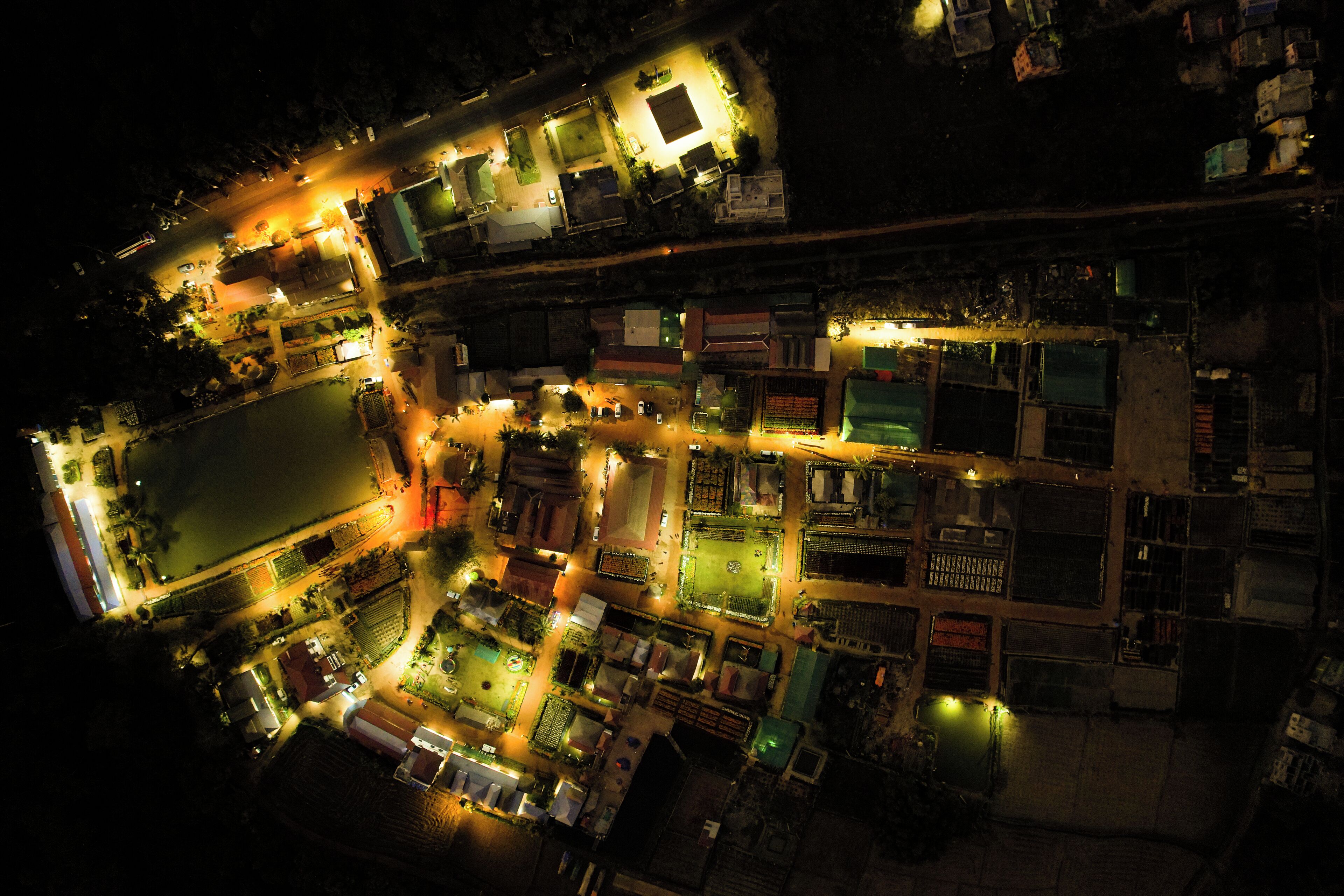 An aerial view of a densely packed urban area with illuminated buildings and streets at night.