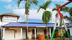 A BAXIALATA hotel with a blue roof, a thatched-roof structure, and a swing set. - Hotel Banalata (Bishnupur)