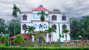 A large white building with a red roof, multiple windows, and a central entrance. - Hotel Banalata (Bishnupur)