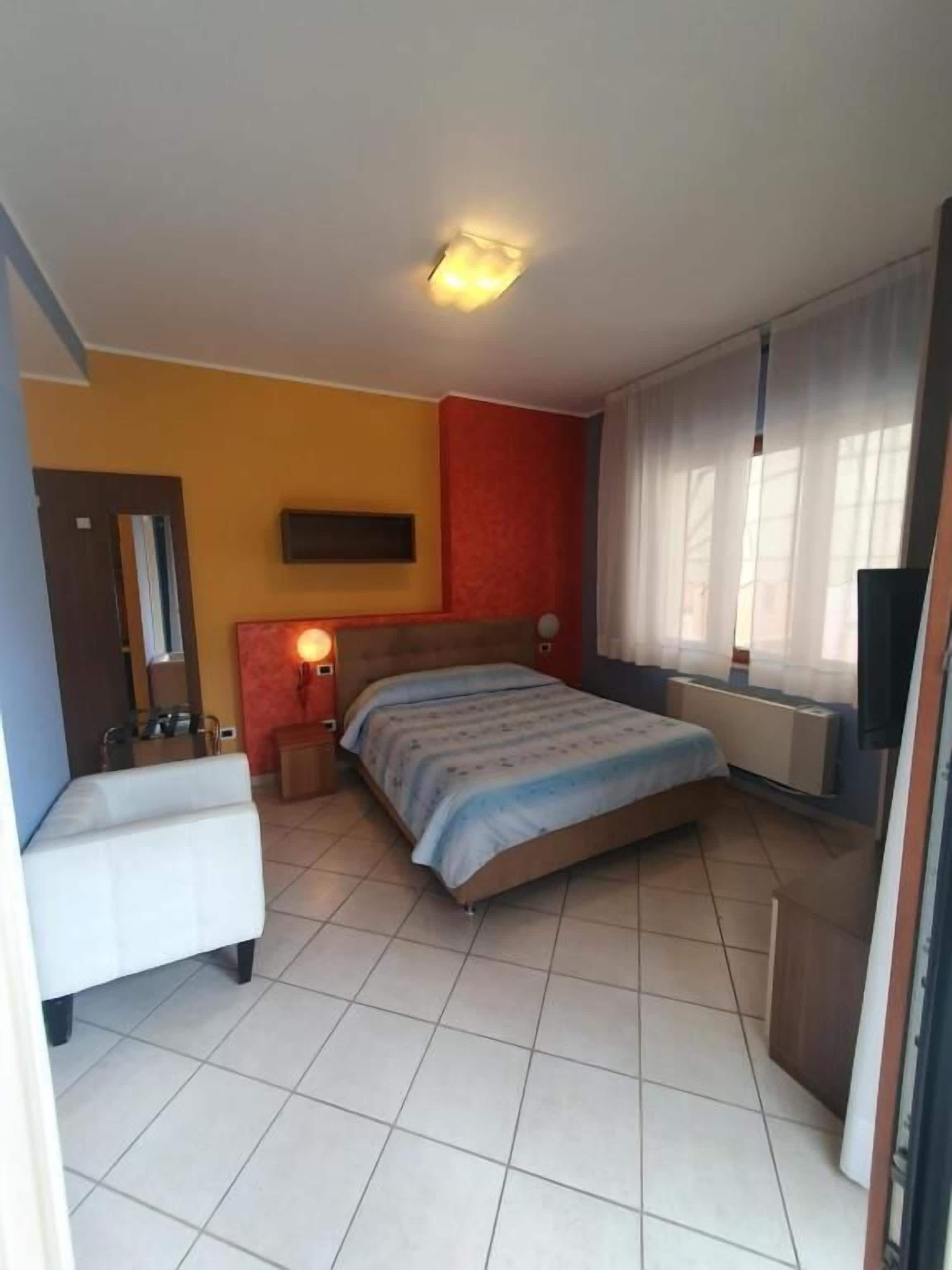 Ein Schlafzimmer mit einem Bett, Nachttischen, einem Spiegel, einem Heizkörper und einem Fernseher.