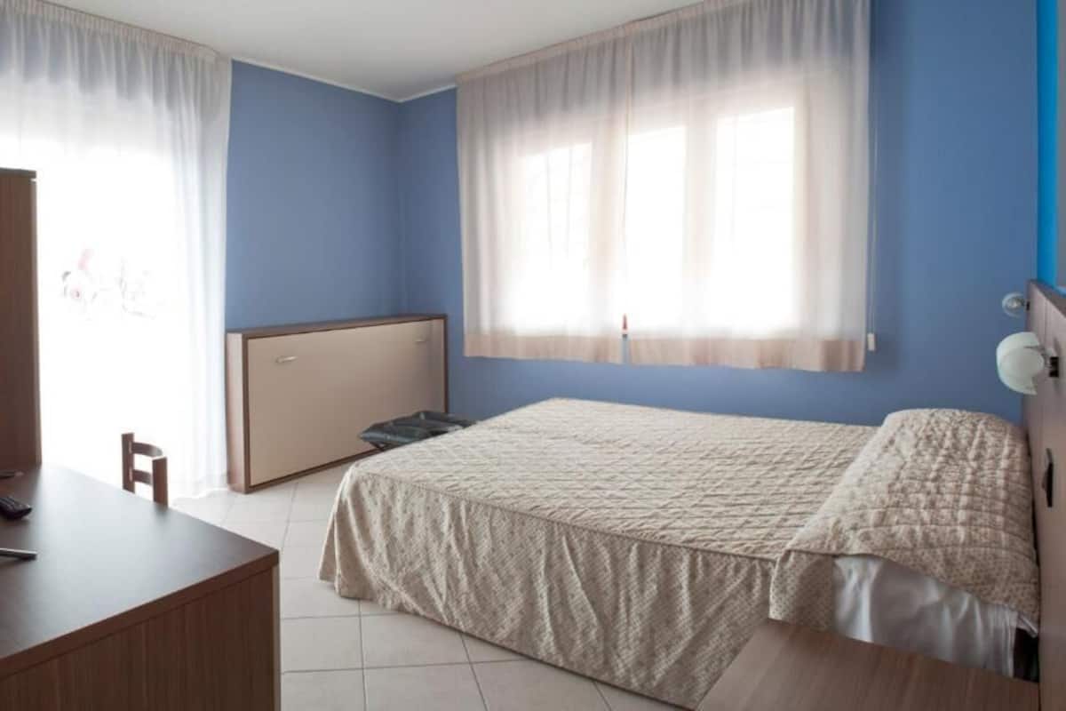 A bedroom with a bed, a desk, and a wardrobe.