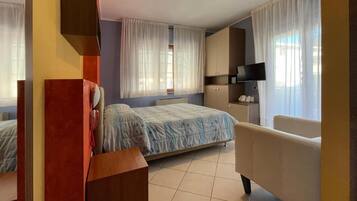 Une chambre d’hôtel avec un lit, un canapé, une télévision et un bureau.