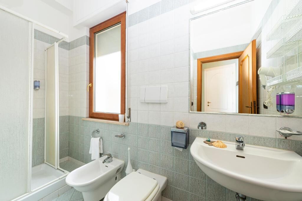 A bathroom with a shower, bidet, toilet, and two sinks.