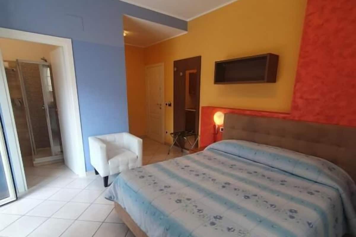 A bedroom with a bed, a chair, a sliding door, and a small table.
