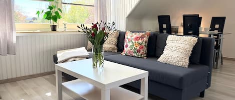 A modern living room with a sofa, a coffee table, and a window with curtains.