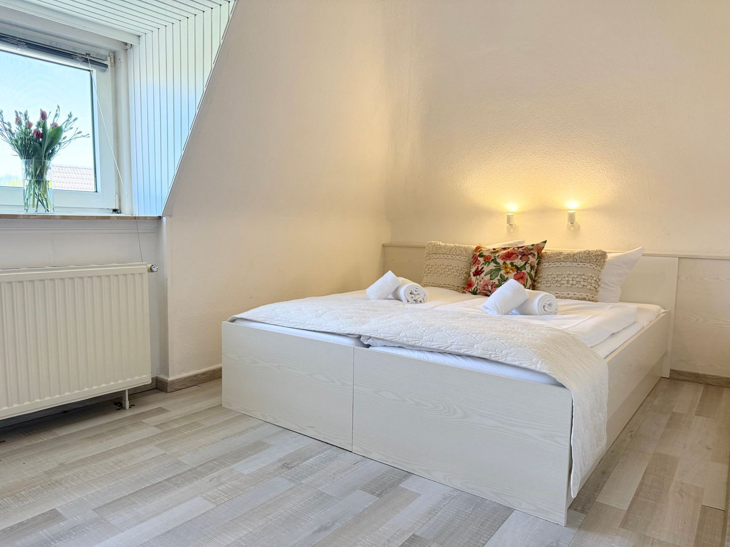 A bedroom with a bed, a window, and a radiator.