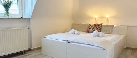 A bedroom with a bed, a window, and a radiator.