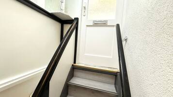 Eine Treppe mit einer weißen Tür am oberen Ende, einer Handläufe und einer strukturierten Wand.