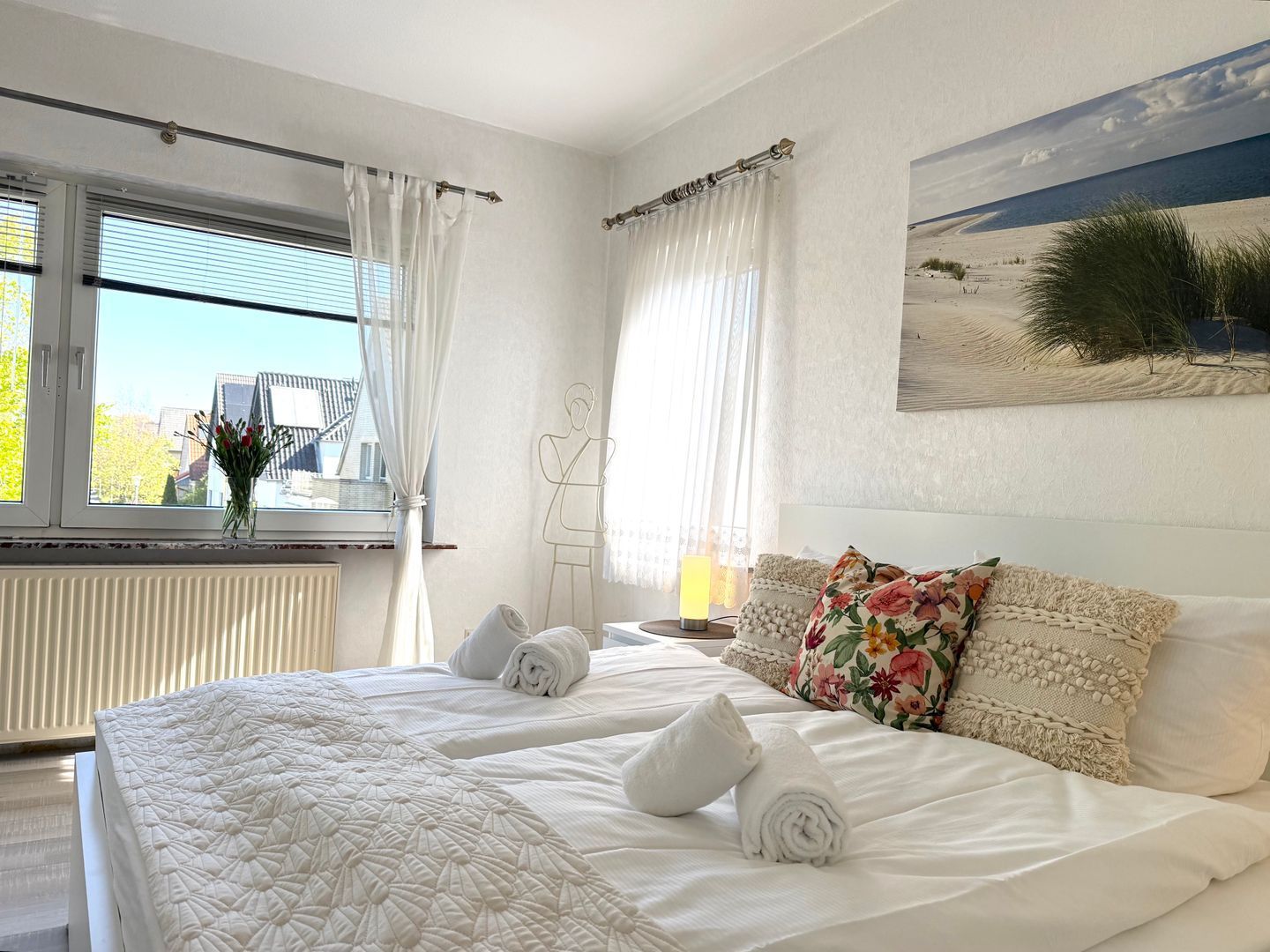 A hotel room with a large bed, a view of the sea, and a painting on the wall.