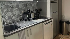 Cozinha moderna com uma pia de aço inoxidável, chaleira e micro-ondas na bancada.