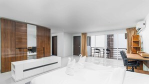 A modern hotel room with a large bed, a desk, and a balcony with a view. - Great Ocean View 2Br Near Beach C265 (Patong)