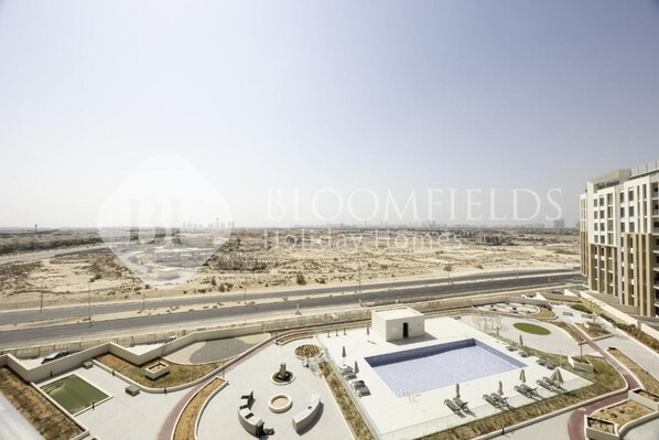 A rooftop pool area with a view of the desert landscape. - Bloomfields 1BR-Rukan-Wadi Al Safa 7 (Dubai)