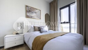 Quarto de hotel moderno com uma cama grande, uma mesa de cabeceira, cortinas na janela e um quadro na parede.