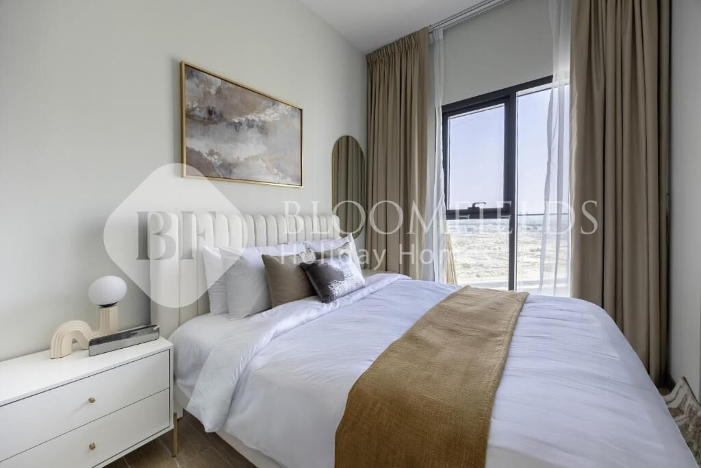 A hotel room with a large bed, a bedside table, a lamp, and a window with curtains.