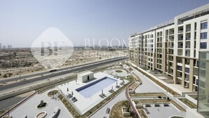 Um complexo de apartamentos moderno com piscina, áreas ajardinadas e vista para a cidade.