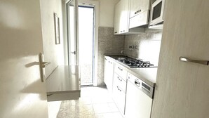 Una cocina con armarios blancos, microondas, estufa y lavavajillas.