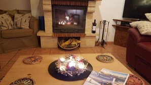 Een woonkamer met een stenen openhaard, een bank, een salontafel met decoratieve objecten en een televisie.