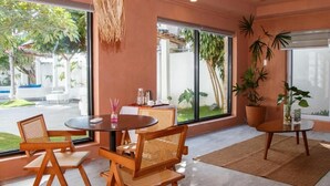 A modern room with a round table, wicker chairs, a ceiling fan, and large windows offering a view of the outdoors. - Casa Mezcaleria (Boracay Island)