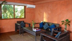 A room with a sofa, two chairs, a coffee table, and a window with a view of palm trees. - Casa Mezcaleria (Boracay Island)