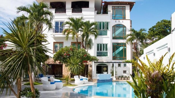 A modern hotel with a swimming pool, surrounded by palm trees and greenery. - Casa Mezcaleria (Boracay Island)