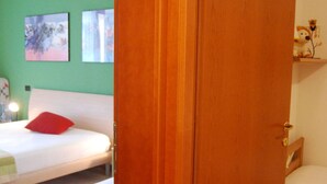 Un dormitorio con cama, puerta de madera y pared verde.