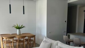A modern living room with a white sofa, a wooden dining table, and a potted plant. - Villa Mae by ΜΡS (Agkeria)