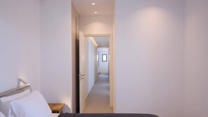 A bedroom with a bed, a bedside table, and a door leading to a hallway. - Villa Mae by ΜΡS (Agkeria)